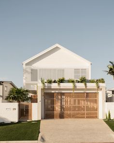 a white house with palm trees in the front yard and an attached garage door to it