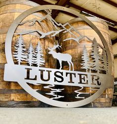 a metal sign that reads luster with a deer in the middle and trees around it