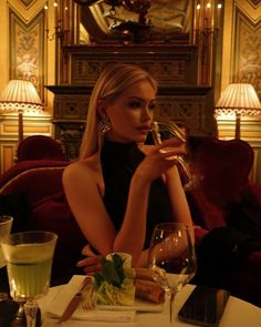 a woman sitting at a table drinking wine