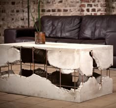 a coffee table made out of concrete with a plant in the center and some rusted metal bars around it