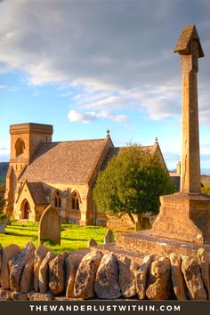 an old church with a tall stone obelisk in the foreground and green grass on the other side