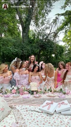 a group of women in pink dresses standing around a table with cakes and cupcakes on it