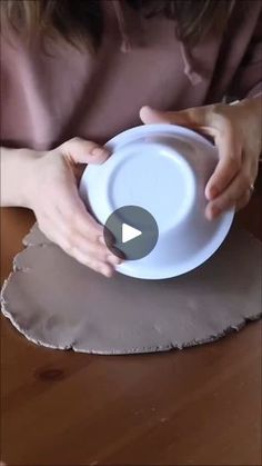 a person holding a white plate on top of a wooden table in front of a woman