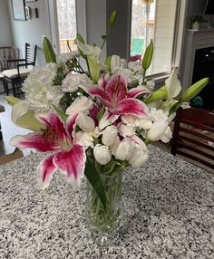 a vase filled with pink and white flowers on top of a table