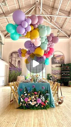 a room filled with lots of balloons and flowers on top of a wooden floor next to a table