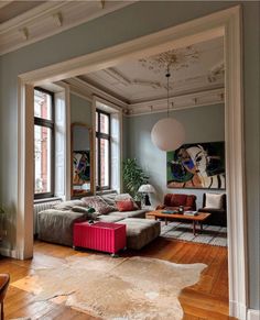 a living room filled with lots of furniture next to two windows and a painting on the wall