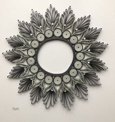 a circular metal wall decoration with candles in the center and leaves around it, on a white background