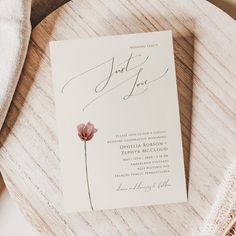 a wedding card with a flower on it sitting next to a white napkin and cloth