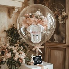 a baby girl bodysuit on top of a box next to flowers