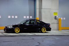 a black car with gold rims parked in front of a garage