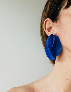 a close up of a person wearing large blue earrings and a white background