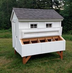 a white chicken coop sitting on top of a lush green field