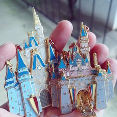 a person holding three pin badges in their hand, each with a castle on it