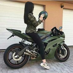 a woman sitting on top of a green motorcycle