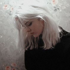 a woman with white hair standing in front of an umbrella