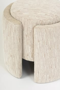 an upholstered stool with two legs and a circular seat on the bottom, in beige