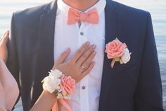 a man in a tuxedo and woman wearing flowers on their lapels holding each other's hands