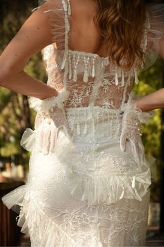 the back of a woman's dress with white lace and ruffles on it