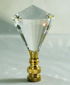 a gold and clear diamond shaped object on a white surface