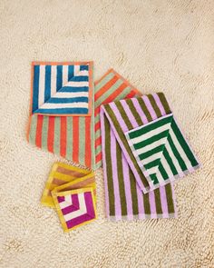 four colorful striped towels laying on top of a white rug