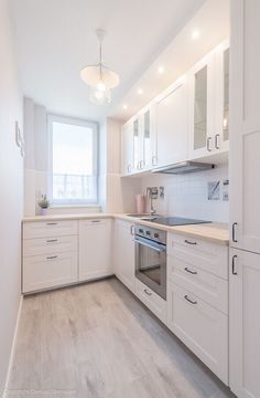 an empty kitchen with white cabinets and wood flooring is seen through a mirror frame