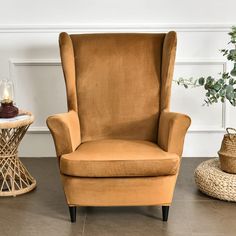 a brown chair sitting on top of a hard wood floor next to a potted plant