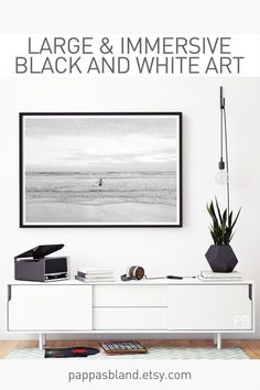 a black and white photo hanging on the wall next to a desk with a plant