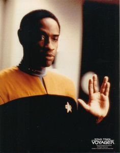 a man in a star trek uniform holding his hand out