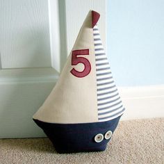 a sailboat shaped pillow sitting on the floor next to a white door with red numbers