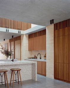 two stools sit in front of a kitchen island with wooden cabinets and counter tops