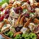 a salad with chicken, cranberries and pecans