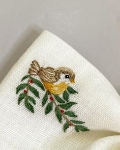 embroidered bird on white linen with green leaves