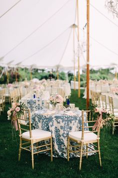 tables and chairs are set up for an outdoor wedding reception in the grass under a tent