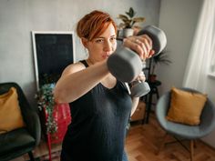 a woman is doing exercises with dumbbells in her living room