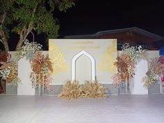 an outdoor stage set up for a wedding ceremony with flowers on the floor and archways