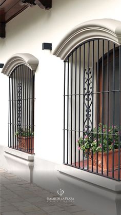 two windows with iron bars and flower boxes on them