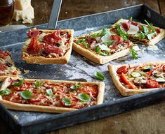 several small pizzas sitting on top of a metal tray