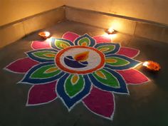 a colorful flower design on the ground with candles around it