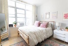 a bedroom with a bed, dresser and large window in the corner that overlooks another room