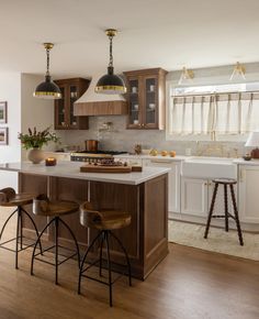 a kitchen with two stools in front of the island and three lights hanging from the ceiling