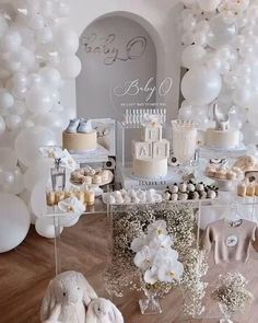 a table filled with lots of white balloons and desserts on top of wooden floors