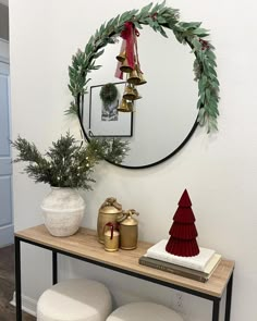 a table with two stools and a round mirror on the wall above it is decorated with christmas decorations