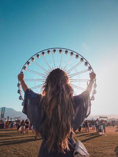 a woman with long hair standing in front of a ferris wheel at an outdoor event