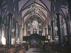 the inside of a church with chandeliers and pews