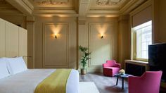 a hotel room with pink and yellow chairs