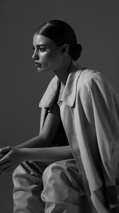 black and white photograph of a woman sitting on a chair with her hands in her pockets