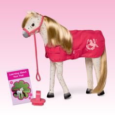 the toy horse is wearing a red coat and has its mane tied up to it's head