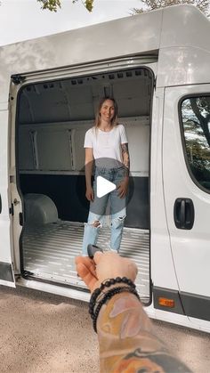 a woman standing in the back of a white van with her hand out to someone