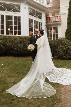 a bride and groom standing in front of a house