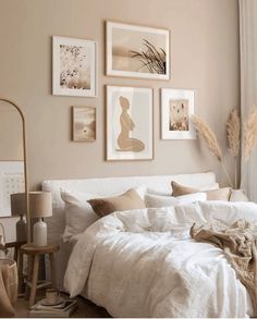 a bed with white linens and pillows in a neutral colored bedroom, surrounded by pictures on the wall